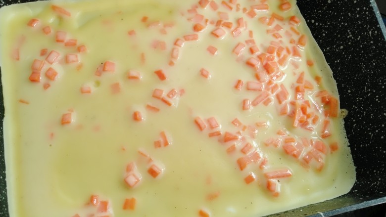 胡萝卜蛋卷,用汤勺舀一勺蛋浆倒入煎锅内晃动均匀