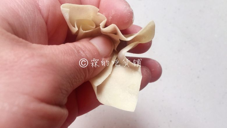 上海三鲜小馄饨,传统小馄饨的包法，用一根筷子挑适量肉馅放在馄饨皮中心位置，然后先把大拇指这边的皮捏下去。