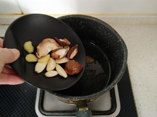 东北乱炖,倒入姜片、香菇、蒜瓣继续炒香。