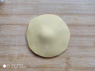 土豆造型豆沙包(馒头),取一个黄面团先揉光滑，擀成四周薄中间厚的面皮。
