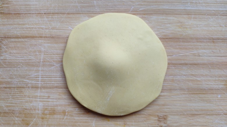 土豆造型豆沙包(馒头),取一个黄面团先揉光滑，擀成四周薄中间厚的面皮。
