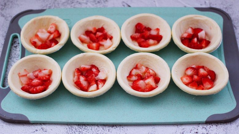 草莓芝士酥～蛋挞皮版,看见蛋挞皮软化以后，把切丁的草莓均匀的放到蛋挞皮里。