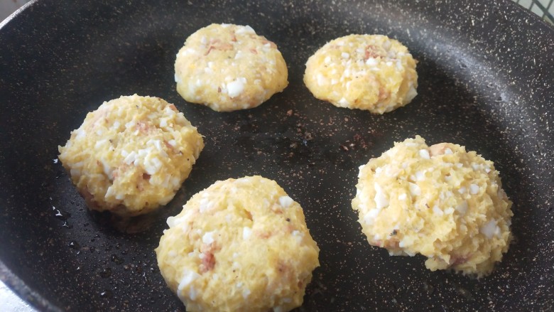 土豆泥火腿鸡蛋饼,揉成团后，锅中放油开始煎，煎至两面金黄。