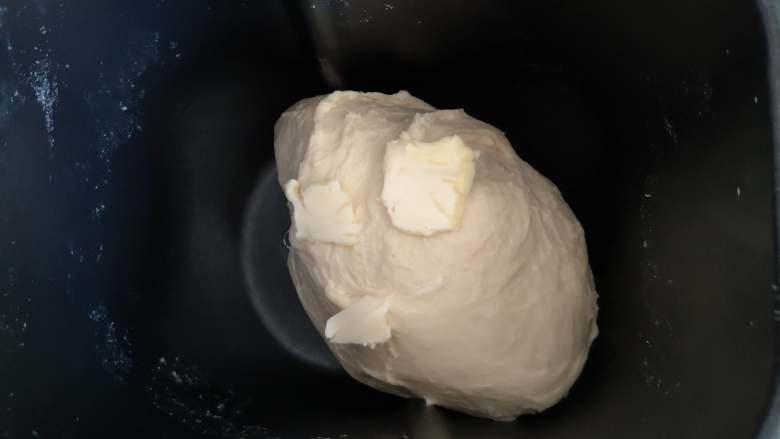 葡萄干小面包,当面团能拉出较粗的薄膜时，加入黄油，继续揉面。