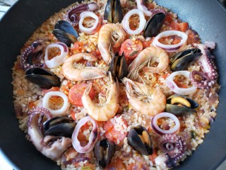 西班牙海鲜饭,将所有海鲜均匀的铺在饭上，并往下轻轻按压至半埋在饭中。