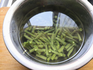 凉拌豆角,再切成1寸左右的长度，锅里加入适量的清水，烧开后把豆角焯水断生，焯水的时候在锅里放少许盐，这样豆角就会变在翠绿色，很漂亮，