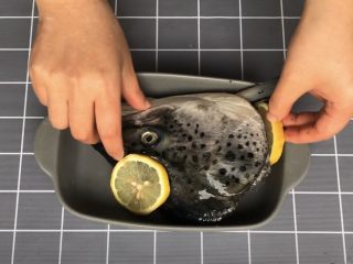 盐烤三文鱼头,将按摩好的鱼头放入烤盘中，摆上切好的柠檬