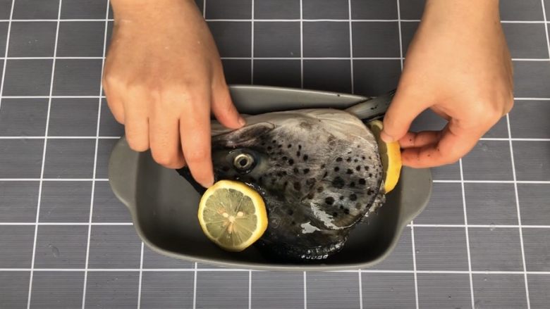 盐烤三文鱼头,将按摩好的鱼头放入烤盘中，摆上切好的柠檬