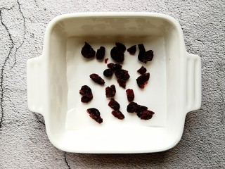 蔓越莓酸奶糕,取一个容器，铺上一层油纸，撒上切碎的蔓越莓