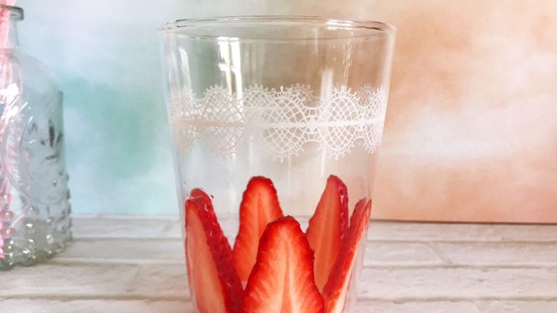 粉嫩少女心～草莓酸奶昔,将草莓片贴在玻璃杯内，如图所示