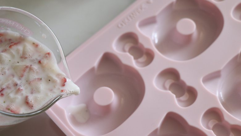 自制健康美味的草莓牛奶果冻,倒入学厨的硅胶甜甜圈模具中。倒之前，底部最好放置一个硬的平盘，更加方便移动。
