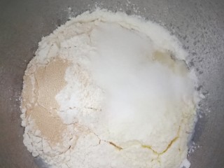 椰蓉面包,除了黄油面包的所有原料放进厨师机里揉面十分钟左右。揉到初级扩展阶段也就是撕开面团，有剧齿状，这个时候放入软化的黄油，继续揉。