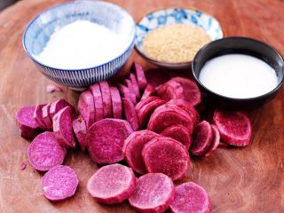 紫薯酸奶果仁芝麻饼,把去皮的紫薯用刀切成薄片，称重糯米粉和酸奶，还有白芝麻。