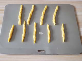 自制磨牙棒,捏住长条的两端反方向扭几下，放在烤盘上；