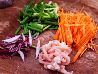 三丝春卷～饺子皮版,用刀把猪肉切成细条，把洋葱和胡萝卜切丝，把韭菜切段。
