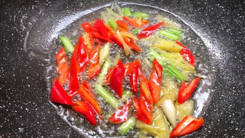芦笋炒鱿鱼,热锅放入适量油，把葱白和姜丝放入爆香，再放入红辣椒翻炒至断生。
