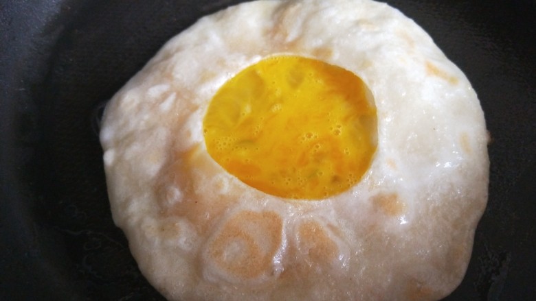 早餐鸡蛋灌饼,用筷子挑开饼口倒入鸡蛋液。