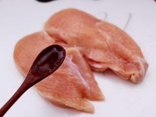 芦笋煎鸡胸肉,用小木槌轻轻捶打鸡胸肉，然后用刀剖为两半，然后再次捶打后，倒入料酒去腥。