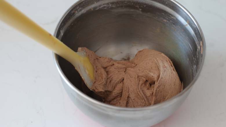 咖啡巧克力核桃脆皮磅蛋糕,用刮刀翻拌至干粉消失的状态。注意不要翻拌过度，否则会使面糊起筋，影响磅蛋糕膨胀长高。最后得到的是#基础面糊#