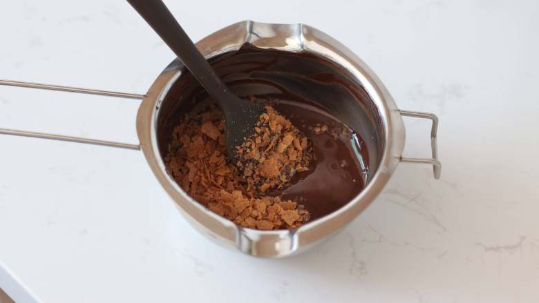 咖啡巧克力核桃脆皮磅蛋糕,纯可可脂巧克力币隔热水融化（水温不要超过50℃）后加入巧克力脆片拌匀。稍微放一会降温
