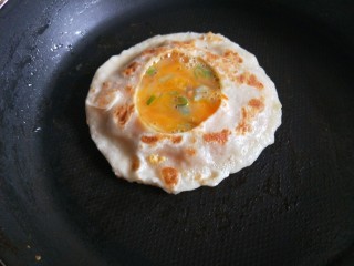 猪肉胡萝卜馅灌鸡蛋饼,碗中打入一个鸡蛋，加入适量香葱，少许盐搅拌均匀，把鸡蛋灌入饼口。