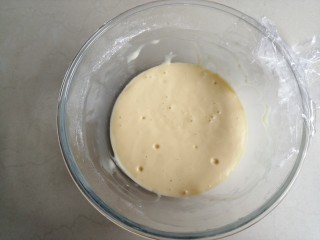 酵母版炼奶松饼,盖上保鲜膜，在室温下发酵到表面有气泡，体积是原来的两倍大
