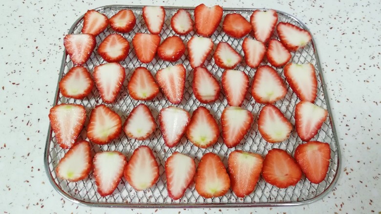缤纷水果干,淡盐水泡过的草莓清洗干净，用厨房用纸吸干水分，一切两半摆在烤网上。