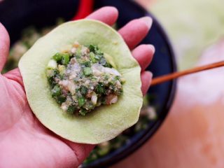 双色西葫芦韭菜生煎包,擀好的面皮加入调制好的馅料。