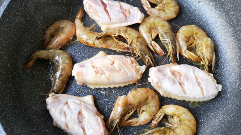 麻辣香锅——麻辣界的扛把子,下入腌好鸡翅（未打花刀一面先入锅）和虾中小火煎。