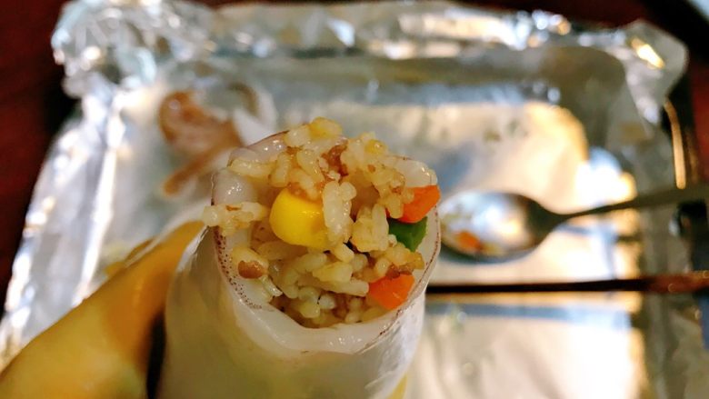 烤鱿鱼包饭,把炒好的米饭塞入鱿鱼筒内。