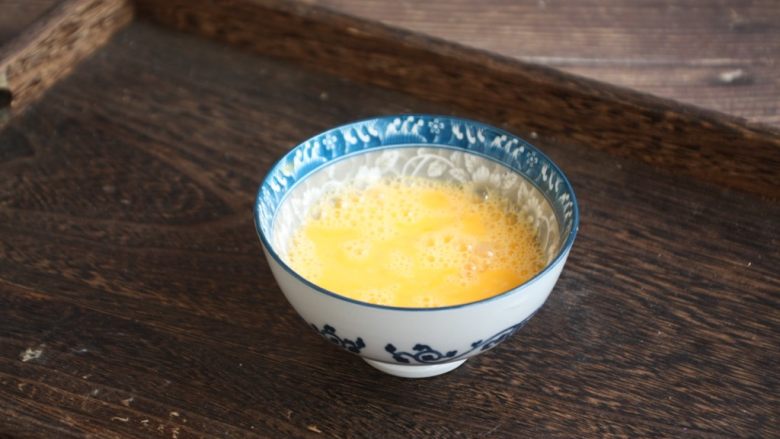 木耳菠菜炒鸡蛋,将鸡蛋磕入碗里，用筷子打散。