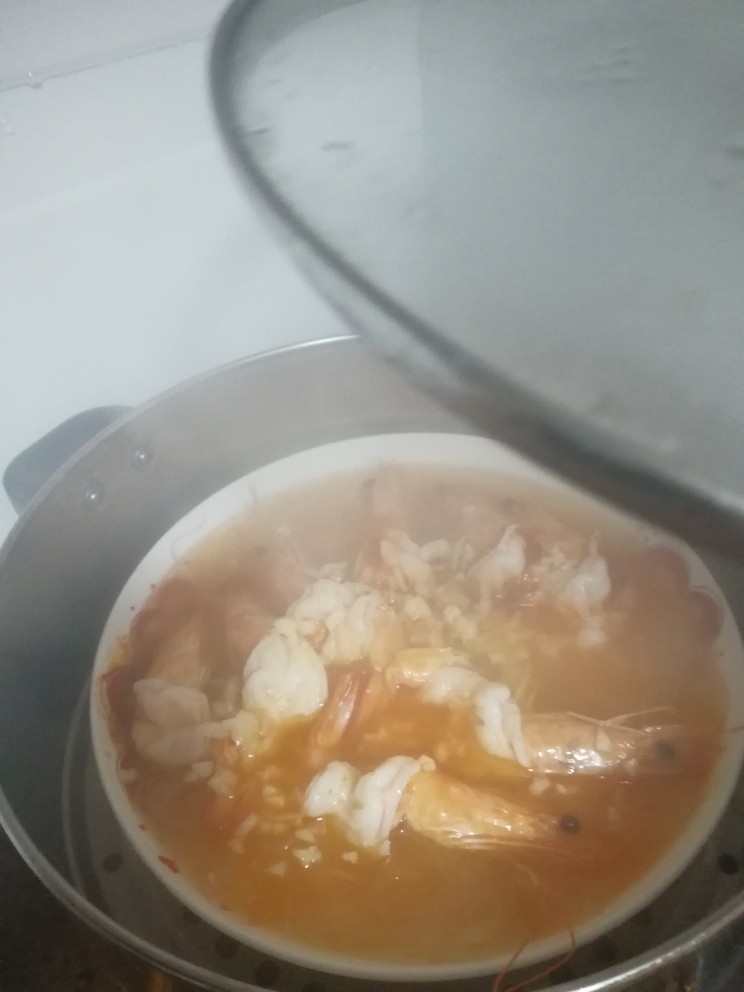 家烧虾,打开蒸锅锅盖，冒着蒸汽呢，小心烫，把蒜末均匀潵在虾上，然后淋上热油，把你刚才锅里煮的玉米油都淋上去。
