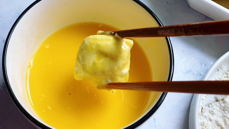 锅包豆腐,然后把滚了面粉的豆腐放入到打散的蛋液里，让每个面都裹上蛋液。裹上蛋液再煎比直接下锅煎色泽更漂亮。