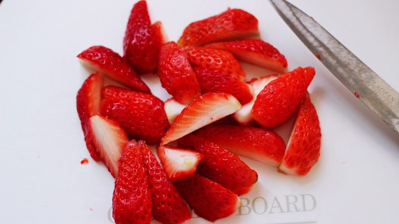 牛奶草莓奶昔,把浸泡好的草莓洗净后，用刀把草莓一切4开。