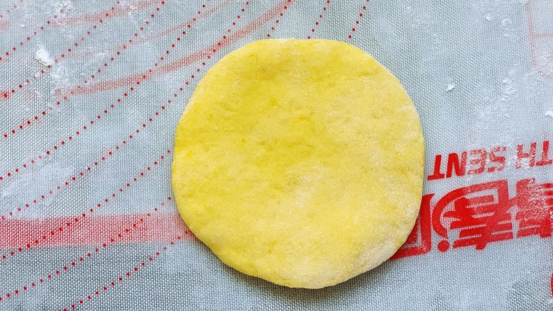 南瓜黑芝麻红糖饼,取一个小剂子搓圆后按扁，用擀面棍稍微擀大一点。
