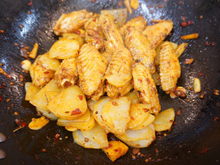 麻辣鸡翅,最后放入土豆片不断翻炒均匀，等到土豆和鸡翅的表面全部沾满酱料，即可出锅