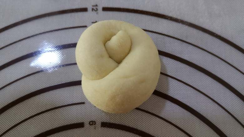 绵软美味的淡奶油花包,长条的一端绕手指一圈，将另一端的顶部从圆孔中穿过来，就形成了一个花的形状，其余的小面团都依此方法操作。