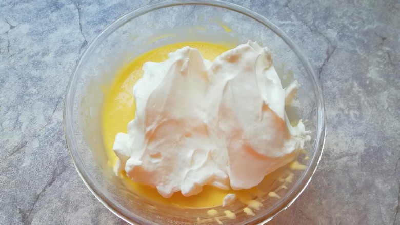 6寸中空戚风蛋糕,打发好的蛋白分成三份，取中间的三分之一加入到蛋黄糊里面，用硅胶刮刀采用切拌和翻拌的方法混合均匀。