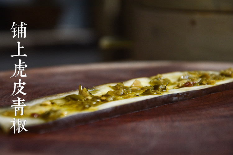 烧椒茄子,将蒸熟的茄子片铺在菜板上，放上三生川虎皮青椒，涂抹均匀。
