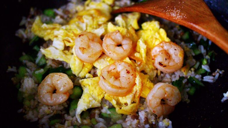 黄瓜虾仁杂粮蛋炒饭,翻炒均匀的杂粮米饭后，倒入炒熟的鸡蛋和虾仁。
