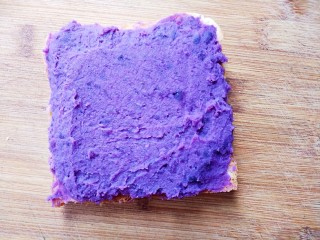 紫薯肉松三明治,将紫薯泥铺在吐司上。