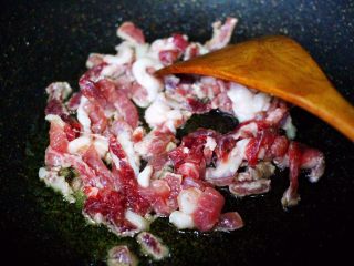 香干肉丝炒韭菜,把腌制好的猪肉放入锅中，用锅铲打散。