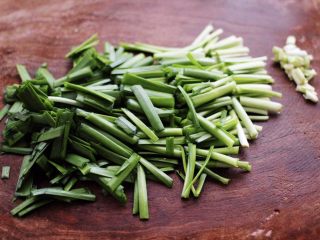 香干肉丝炒韭菜,韭菜摘洗干净后，用刀先把韭菜的根部切出不要，再把韭菜切段备用。