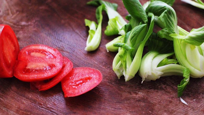 排骨青菜番茄面,把番茄用刀切成薄片，青菜用刀切开。