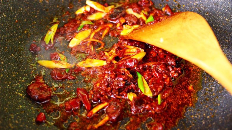 双椒辣爆鸡块,大火把郫县豆瓣酱炒出红油后，爆香葱姜丝。