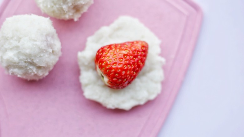 甜糯小可爱草莓大福,取适量山药泥揉成圆球，压扁，将草莓尖朝上放进去。