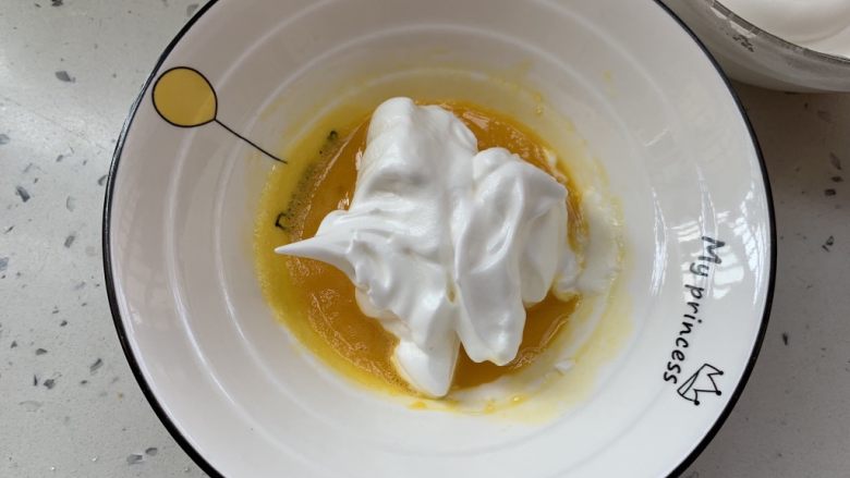 奶香手指饼,取三分之一的蛋白霜，加入蛋黄糊拌匀