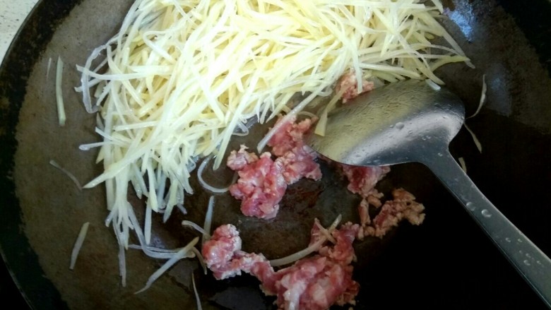 肉沫土豆丝,把 土豆丝铲到一边，放入肉沫翻炒至变白