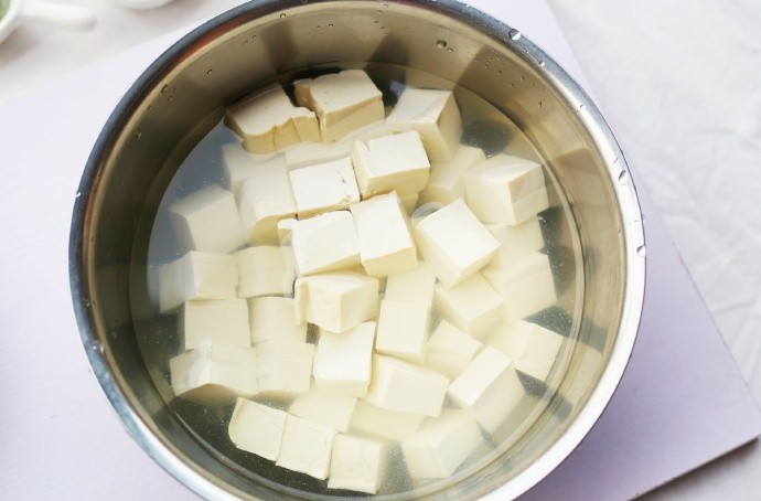 鲜掉眉毛的丝瓜豆腐汤,豆腐切成小块，然后加入淡盐水中浸泡15分钟。（这样一来可以去除豆腥味，二来在炒的时候，可以让豆腐的形状更加完整。）