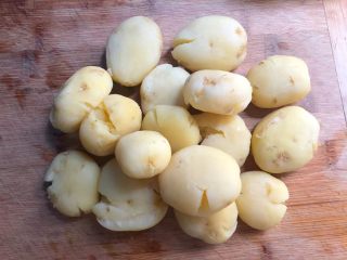 孜然小土豆,小土豆煮熟捞出来，沥干水分，用刀背把土豆拍扁待用。